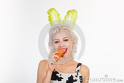 Smile easter. Cute bunny rabbit. Young woman with banny ears eat carrot. Easter bunny dress. Stock Photo