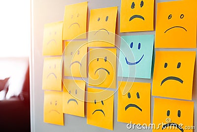 smile face sticky note surrounded by sad face stickynote Stock Photo