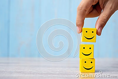 Smile face on yellow wood cube. Service rating, ranking, customer review, satisfaction and emotion concept Stock Photo