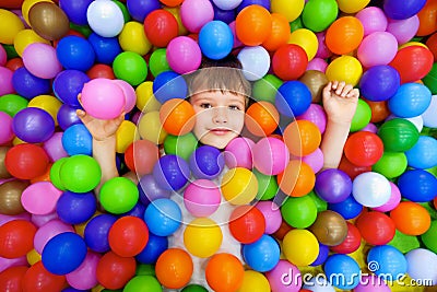 Smile kid lying colorful plastic balls pool. Playroom kids ball pit. Colorful balls dry pool kindergarten playground Stock Photo