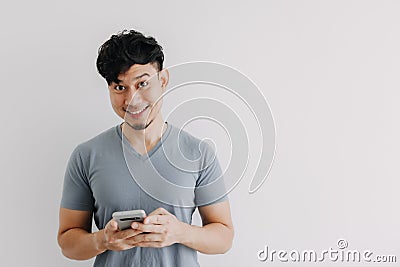 Smile man is happy with the smartphone application isolated on white wall. Stock Photo