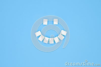 Smile symbol, composed of cubes of sugar on blue background. Concept of sugar leading to caries Stock Photo