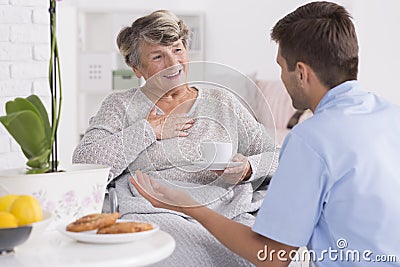 Smiled elder woman and her young male nurse Stock Photo