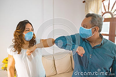 Smiley couple wearing protective face masks waving elbows in the workplace, co-workers wearing face covers protect themselves from Stock Photo