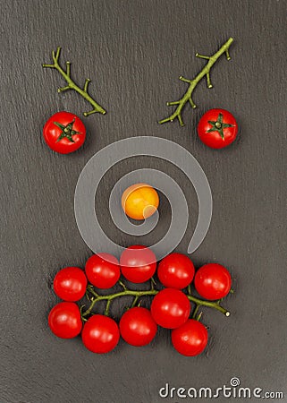 Smiley face with a angry expression. Laying out parts of a human face with vegetables, namely tomatoes and tomato branches Stock Photo
