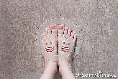 Smiley Face Drawn on Toes. Close Up Female Barefoot On Wooden Floor Background Stock Photo