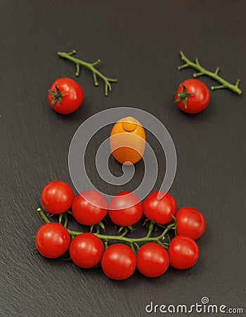 Smiley face with a watchful expression. Laying out parts of a human face with vegetables, namely tomatoes and tomato branches Stock Photo