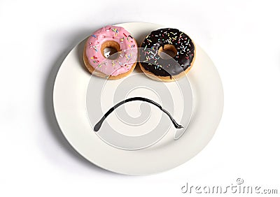 Smiley sad face made on dish with donuts as eyes and chocolate syrup mouth in sugar sweet addiction diet and nutrition Stock Photo