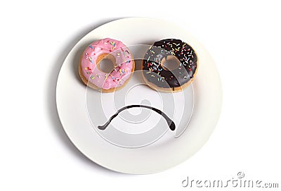 Smiley sad face made on dish with donuts as eyes and chocolate syrup mouth in sugar sweet addiction diet and nutrition Stock Photo