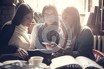 Smiley shocked girls using mobile in cafe. Stock Photo