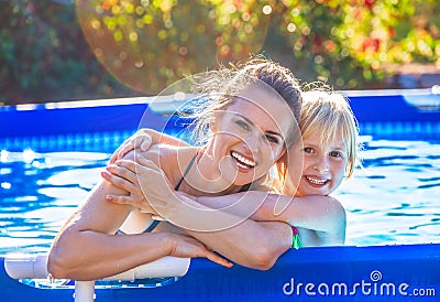 Smiling active mother and child in swimming pool embracing Stock Photo