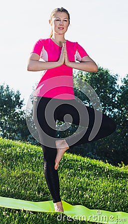 Smiling adult female in pink T-shirt is staying and practising meditation Stock Photo