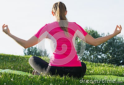 Smiling adult woman in pink T-shirt is sitting her back and practicing meditation Stock Photo