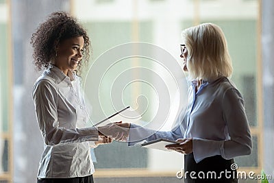 Smiling diverse businesswomen shake hands greeting in office Stock Photo