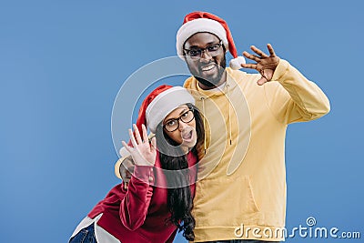 smiling african american couple in christmas hats waving by hands Stock Photo
