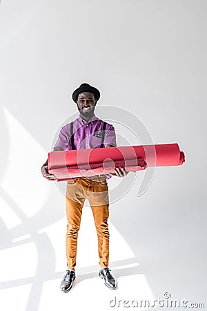 smiling african american in hat holding pink wrapping paper rolls in hands Stock Photo