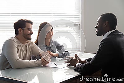 Smiling african american male banker consulting young married couple. Stock Photo