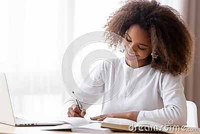 Smiling African American teen girl preparing school homework, using laptop Stock Photo