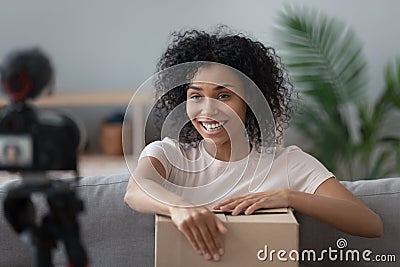 Smiling African American woman blogger recording unboxing parcel video Stock Photo