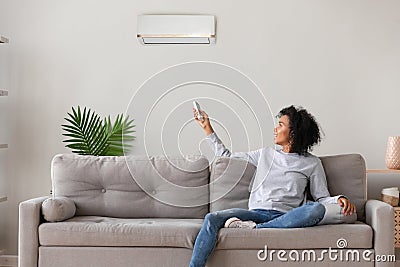 Smiling African American woman using air conditioner remote controller Stock Photo