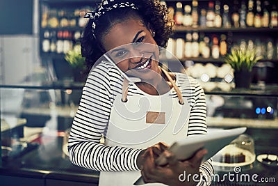 Smiling African entrepreneur talking on the phone in her cafe Stock Photo