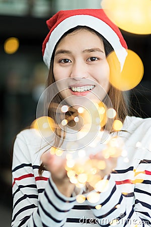 Smiling asia woman wear santa hat holding party string lights wi Stock Photo