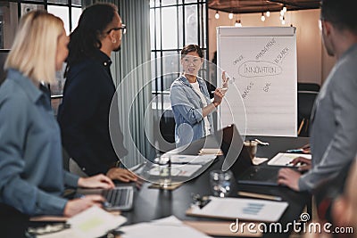 Smiling Asian businesswoman giving a flip chart presentation to Stock Photo