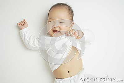 Smiling Asian Chinese baby pulling her shirt playfully Stock Photo