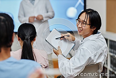 Smiling asian doctor talking to colleague in audience at medical seminar Stock Photo