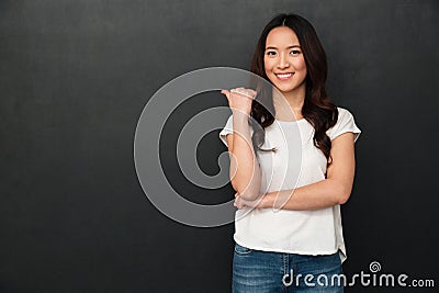 Smiling asian woman in t-shirt pointing away Stock Photo