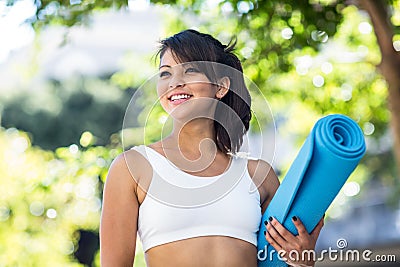 Smiling athletic woman carrying yoga mat Stock Photo
