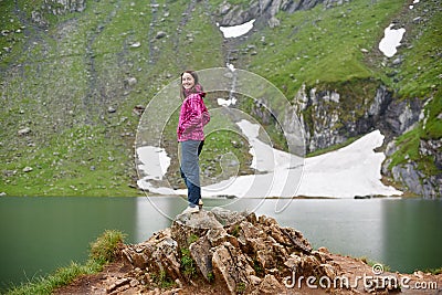 Smiling attractive female posing on rock near green rocky mountains close to artificial Vidraru lake in Romania Stock Photo