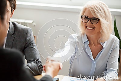 Smiling attractive mature businesswoman handshaking businessman Stock Photo