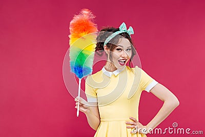 Smiling attractive pinup girl holding colorful duster brush Stock Photo