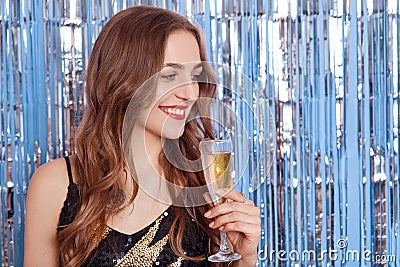 Smiling attractive woman with red lips holding glass of wine or champagne in hands, looking aside with pensive an d happy facial Stock Photo