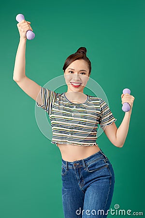 Smiling attractive young Asian woman practicing exercise with dumbell over green background Stock Photo