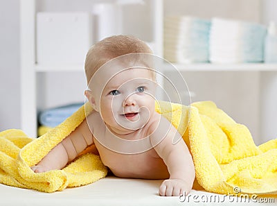 Smiling baby under soft towel. Cute child lying on bed after bathing in bedroom Stock Photo