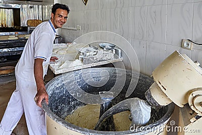 Smiling baker kneads bread dough in kneading machine, Kashan, Ir Editorial Stock Photo