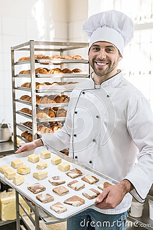 Smiling baker with tray of uncooked dough Stock Photo