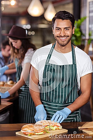 Smiling barista cutting sandwich Stock Photo