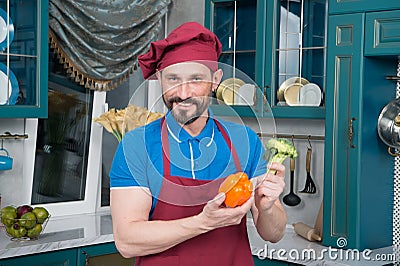 Smiling bearded chef holds paprika and cabbage. handsome guy prepared fresh paprika for lunch Stock Photo
