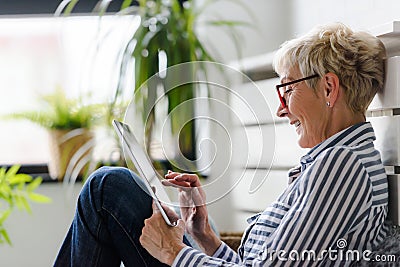 Smiling beautiful senior woman using digital tablet at home Stock Photo