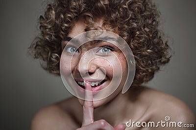 Smiling beautiful young freckled girl with keep quiet gesture, selective focus Stock Photo