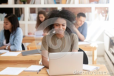 Smiling black girl sit in shared space using laptop Stock Photo