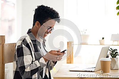 Smiling black woman receiving good news texting message on phone Stock Photo