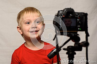 Smiling blond boy in front of the camera lens. Little video blogger. Home studio Stock Photo