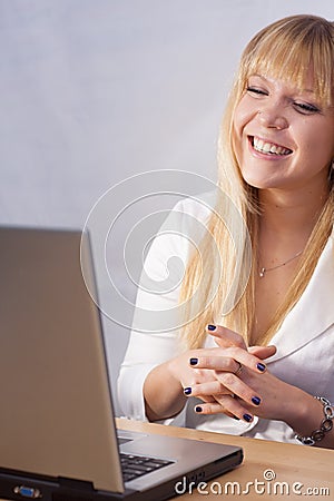 Smiling blond girl chatting online with computer Stock Photo