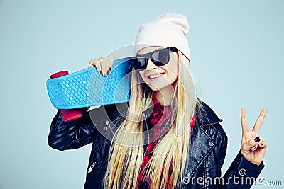 Smiling blond teenager girl in black sunglasses and pink hat with blue skateboard. on white background Stock Photo