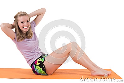 Smiling blond woman training stomach muscles on a mat. Stock Photo