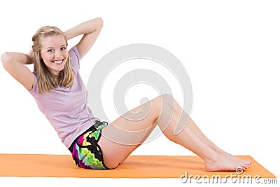 Smiling blond woman training stomach muscles on a mat Stock Photo